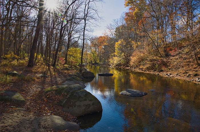 Calm river surrounded by autumn trees, showcasing natural beauty often appreciated in US culture by travelers.