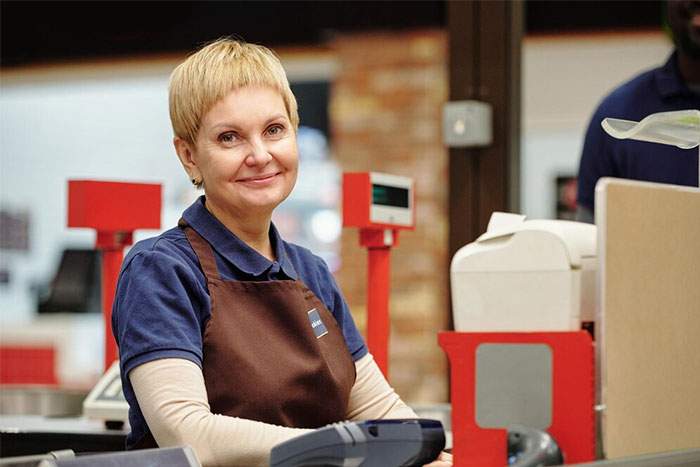 Smiling cashier in a grocery store representing nuances about US culture experienced by travelers.