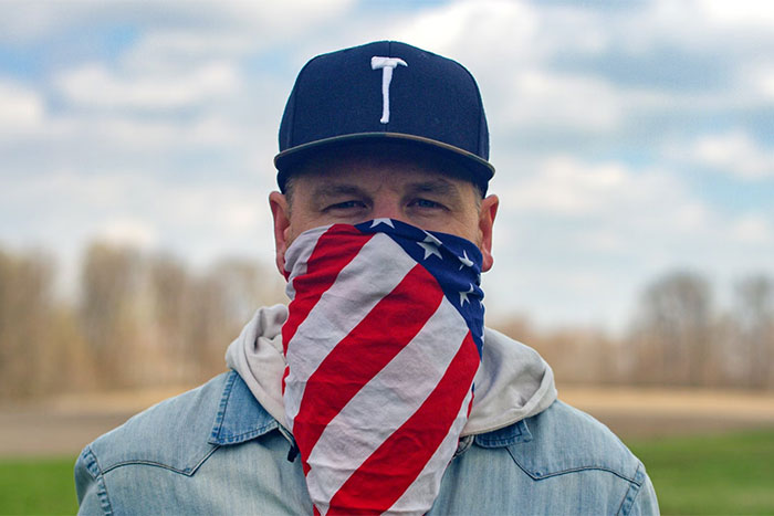 Man wearing a US flag bandana and baseball cap outdoors representing key nuances of US culture for travelers