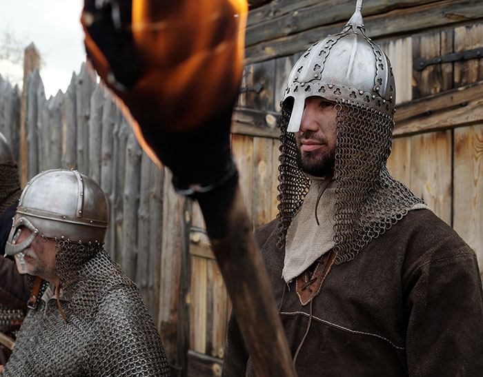 Medieval warriors in chainmail and helmets with a torch, evoking the era of "Love Potions" and ancient traditions.