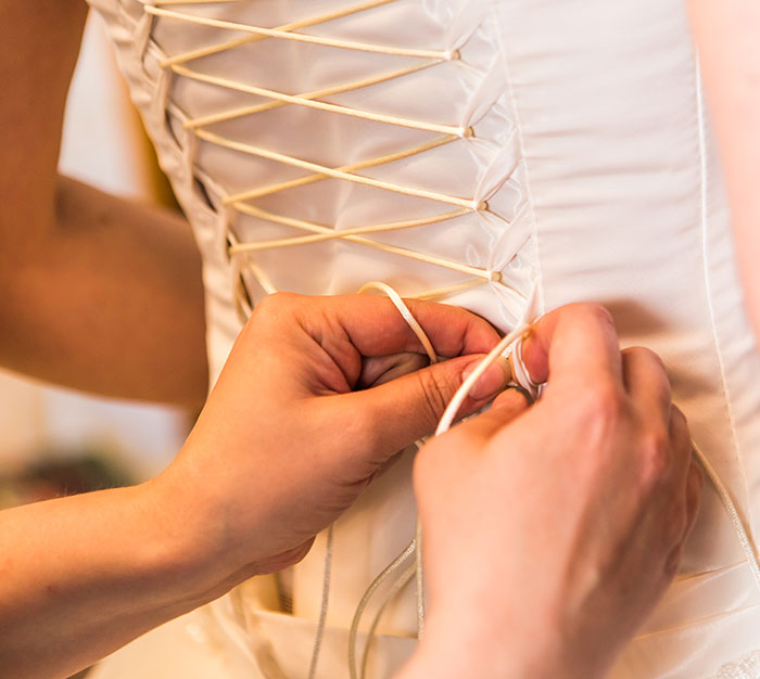 Corset being laced, reflecting a normal medieval task.
