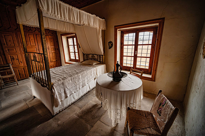 Medieval bedroom with canopy bed and table, highlighting historical charm.