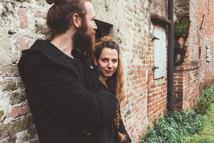 Medieval couple outside a rustic brick building, reminiscent of 'love potion' traditions.