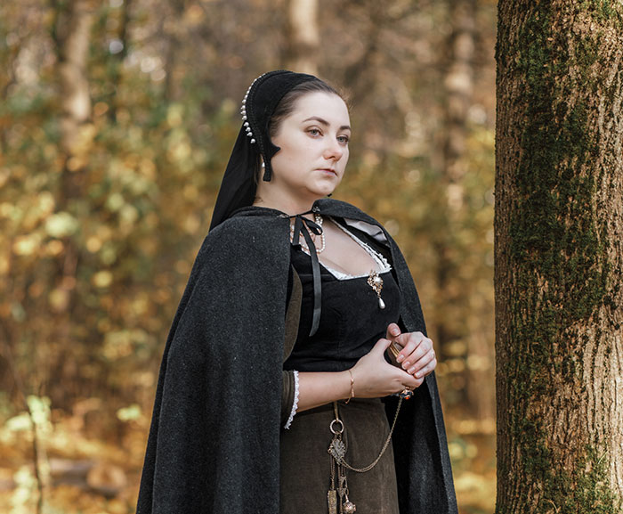Medieval woman in a forest, dressed in historical attire, embodies the era's mystique surrounding love potions.
