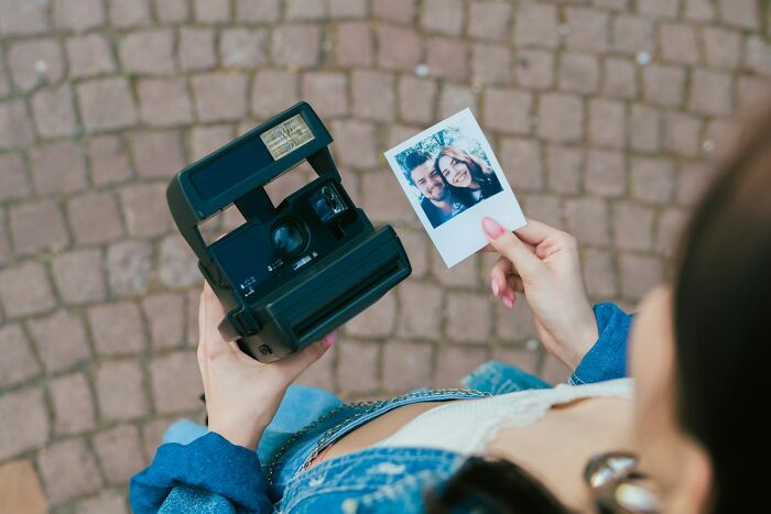 A person holding a camera and a Polaroid photo, capturing a moment in someone else's house.