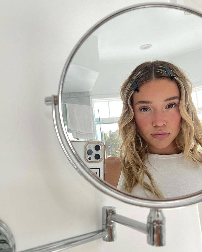 Olivia Ponton with hair clips takes a selfie in a mirror.