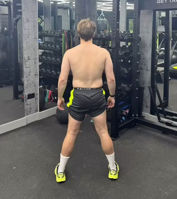 Man in gym wearing shorts and sneakers, showing physique transformation sparking debate between men and women.