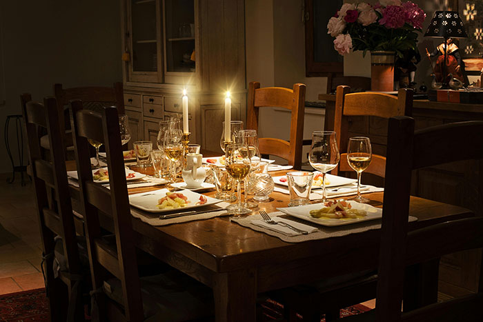Expensive trip-themed dinner table setting with wine glasses, candles, and elegant decor.