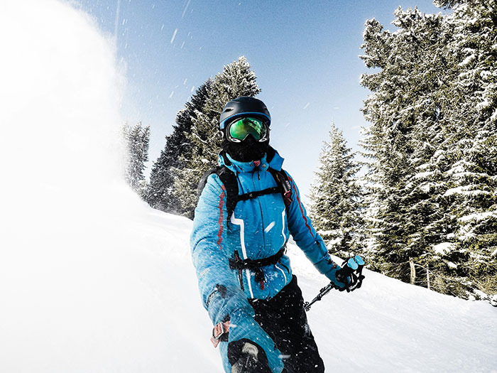 Person skiing in snowy mountains, wearing a blue jacket and helmet, representing out-of-touch wealth activities.