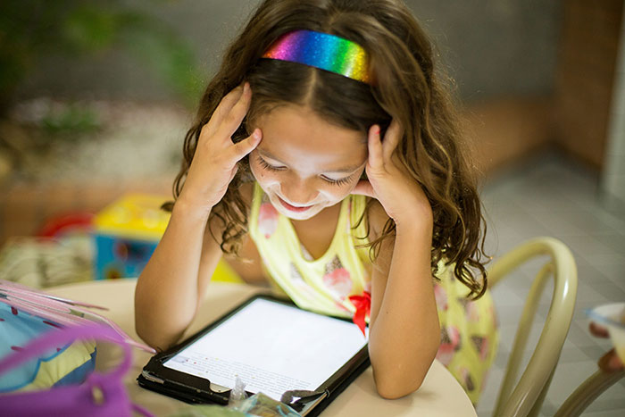 Child with rainbow headband looking at tablet, illustrating out-of-touch moments.