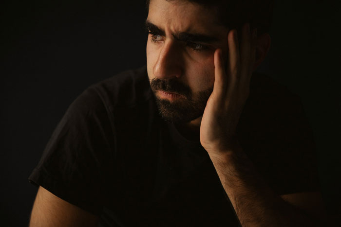 Man in a dark shirt looking pensive, suggesting feelings of low energy.