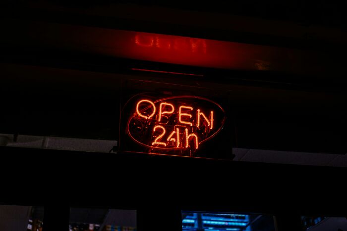 Neon open 24h sign glowing in the dark representing usual things changed by the pandemic.