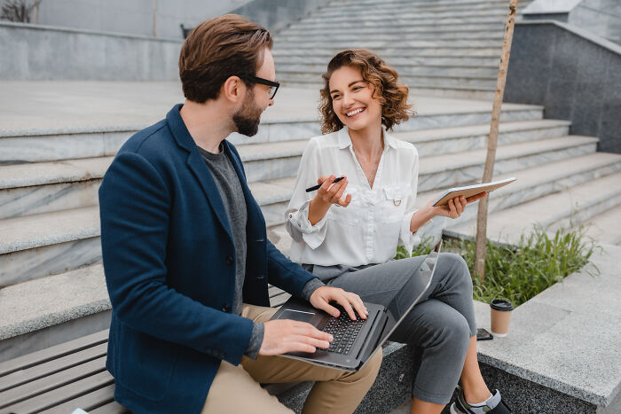 Two professionals working outdoors with a laptop and tablet, illustrating changes in usual things post-pandemic.