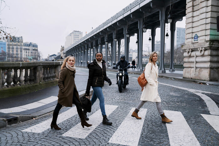 Three women walking across a city street on a crosswalk, symbolizing usual things changed by the pandemic.