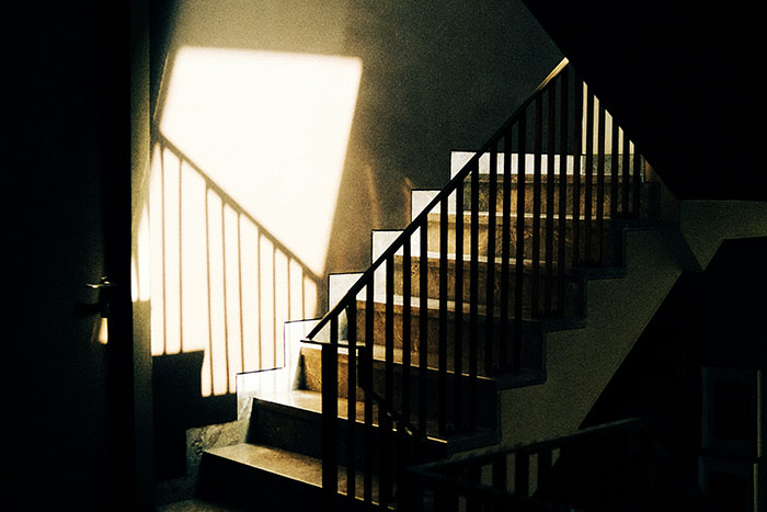 Sunlit staircase symbolizing the journey of kids moving out at 18, casting shadows on the wall.