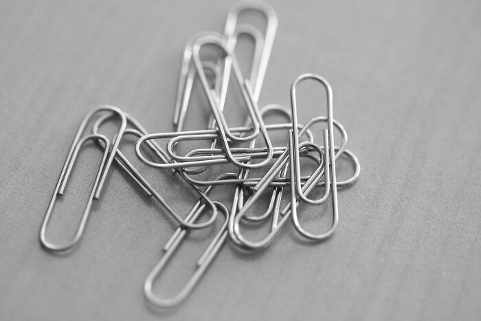 A pile of metal paperclips on a wooden surface, related to disturbing discoveries by doctors in patients.