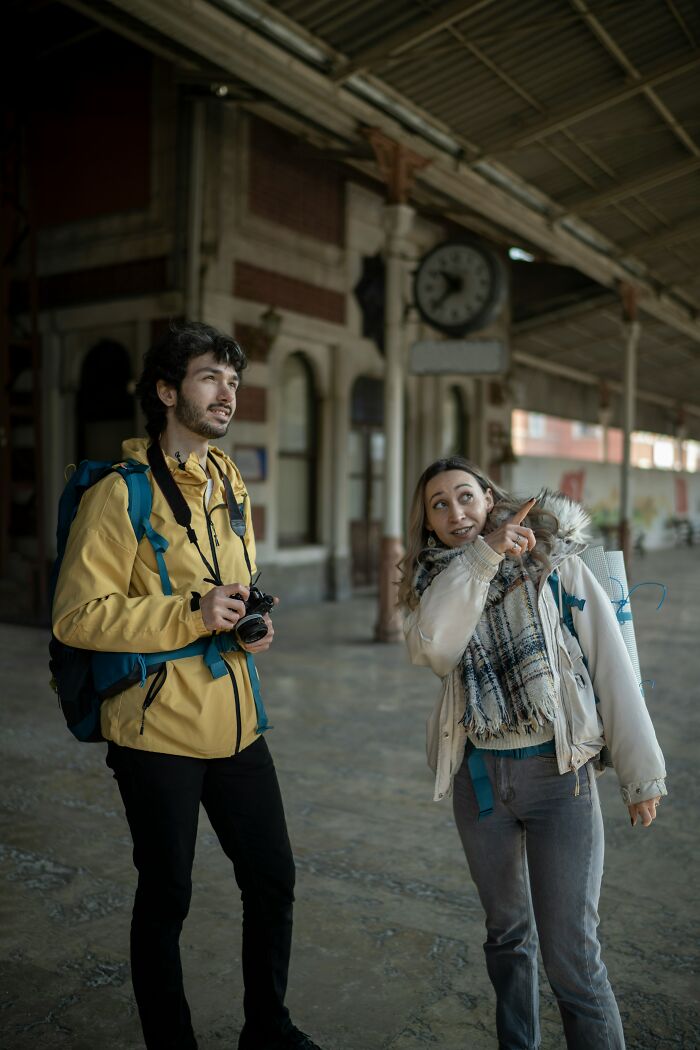 Two people at a train station, one holding a camera, possibly noticing a real-life glitch in the matrix.
