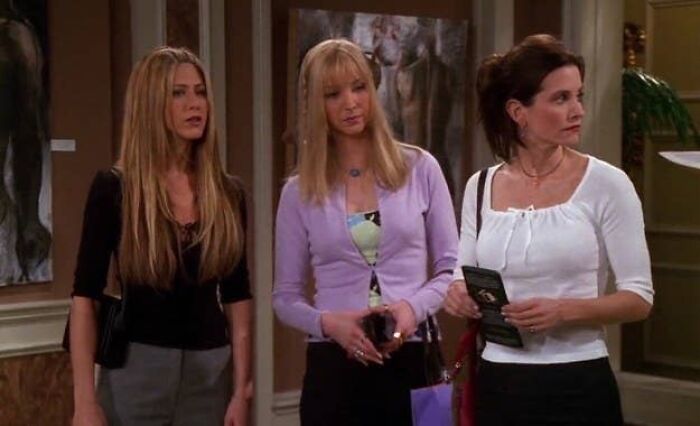 Three people standing in a room, each looking in different directions, resembling a glitch in the matrix.