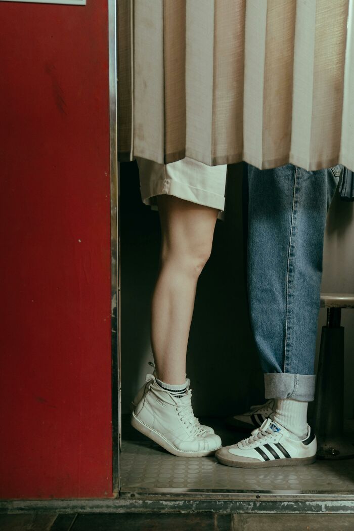 Two people standing close in a tight space, one wearing white sneakers, capturing an unusual real-life glitch moment.