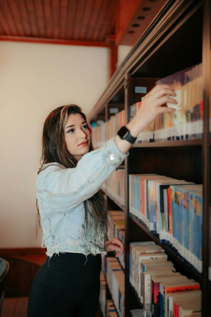 Person reaching for a book on a shelf, wearing a denim jacket, illustrating a real-life matrix glitch moment.