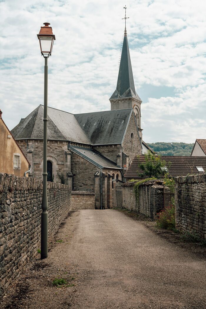 Rustic street with church, featuring an oddly positioned lamppost, suggesting a glitch in the matrix.