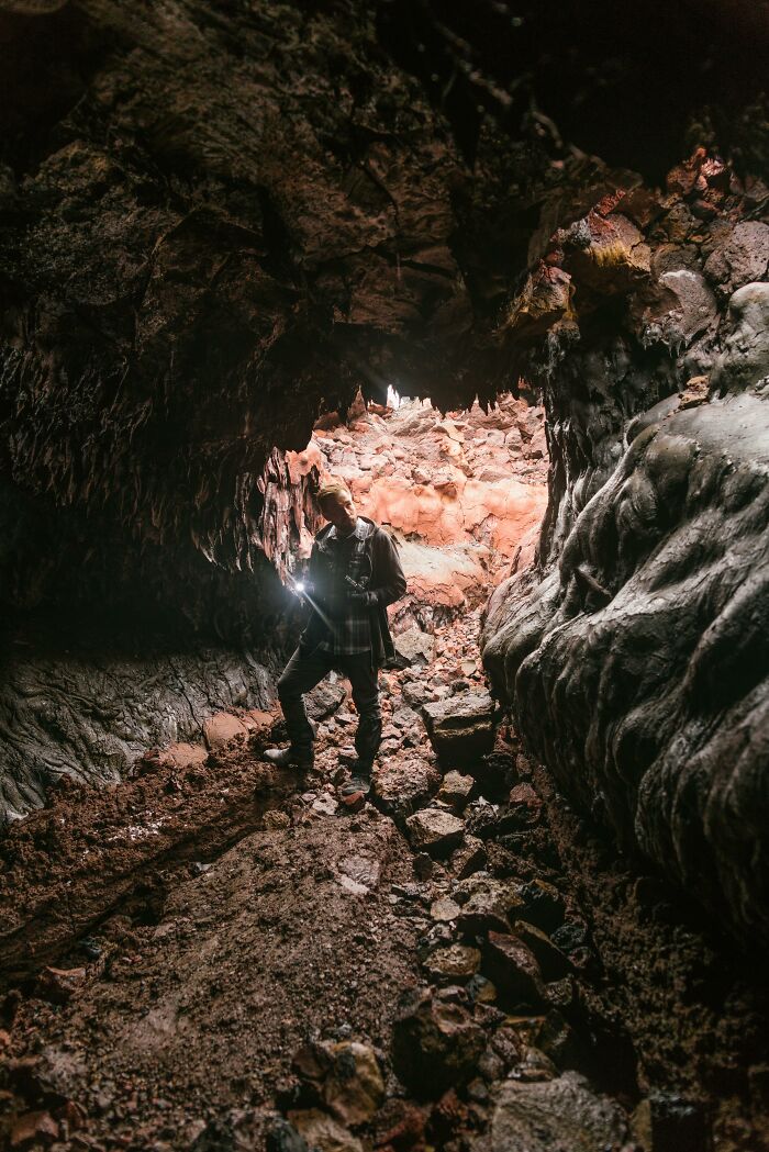 Person exploring rocky cave, flashlight illuminating surroundings, representing a glitch in the matrix moment.