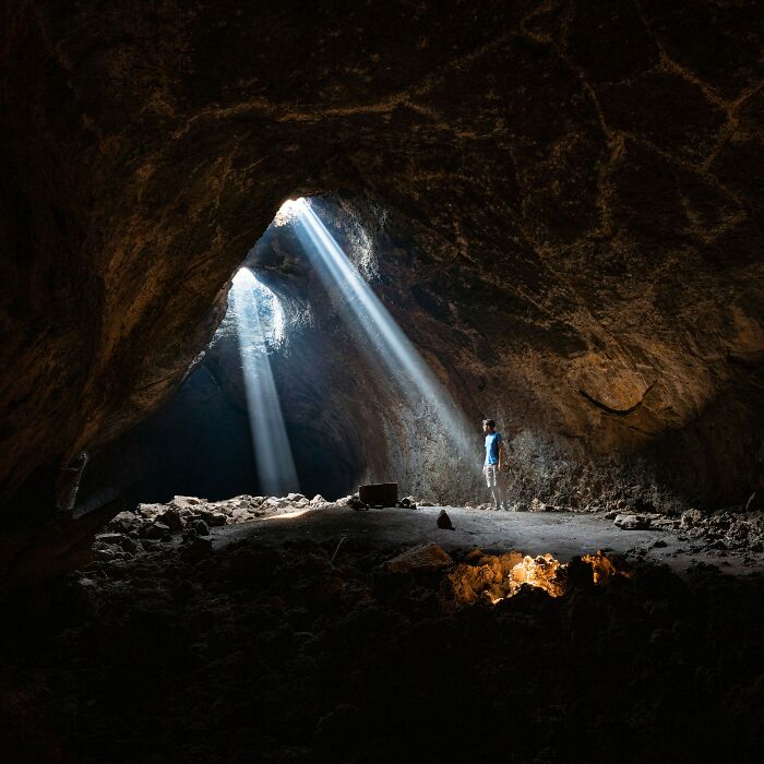 Person standing in a cave with sunbeams creating a matrix-like illusion.