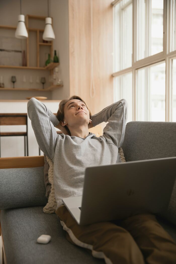 Man relaxing on sofa with a laptop, showcasing unhinged ways to use ChatGPT.