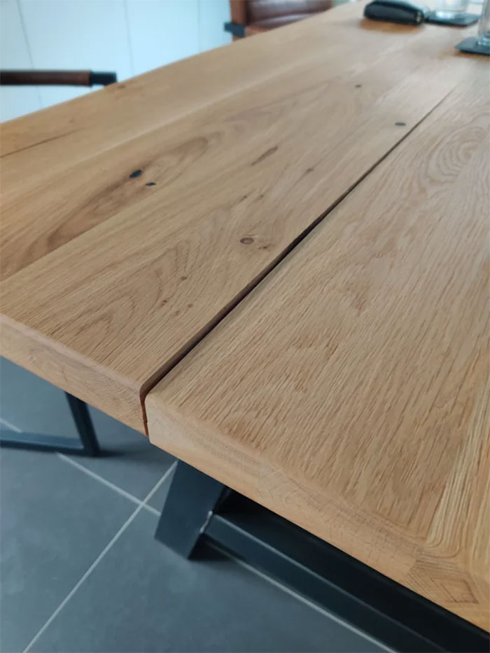Wooden table with noticeable gap and metal legs, highlighting furniture quality issues.