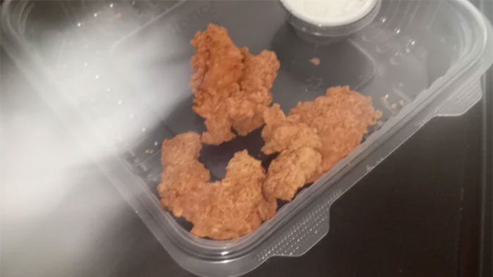 Fried chicken in a takeout container with dipping sauce; items people refrain from using.