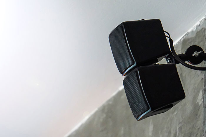 Two black speakers mounted on a ceiling corner, emphasizing vintage audio equipment.