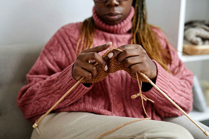 Young person knitting with focus and precision, highlighting a traditional skill often valued by boomers.