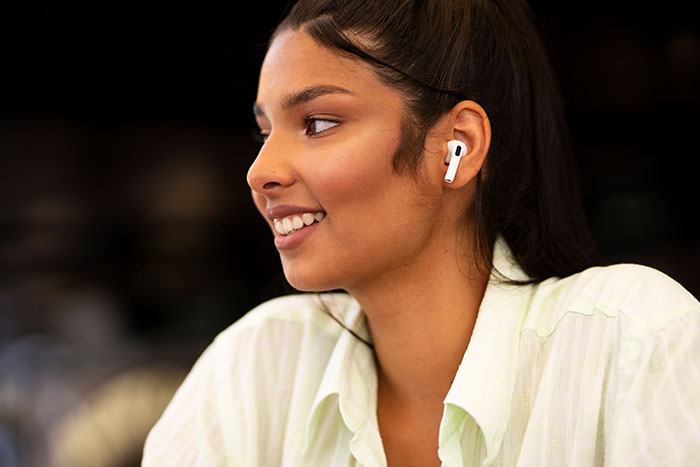 Young person smiling, wearing wireless earbuds, highlighting generational perspectives.