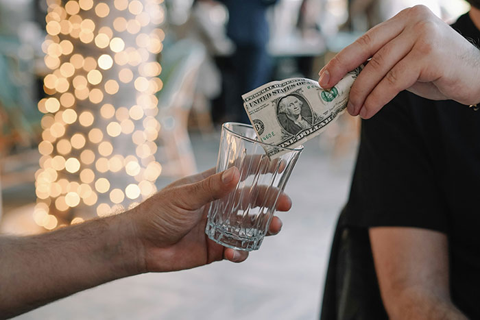 Person handing over a dollar bill into a glass, illustrating things Boomers might be right about.