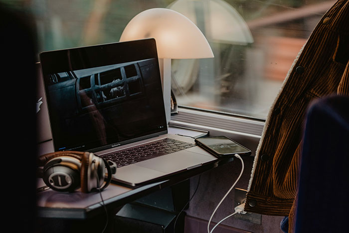 Laptop and headphones on a train table, showcasing physical media magic in a cozy travel setting.