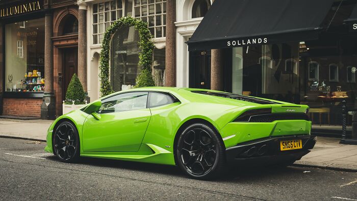 A bright green luxury sports car parked on a city street, showcasing a symbol of wealth and status.