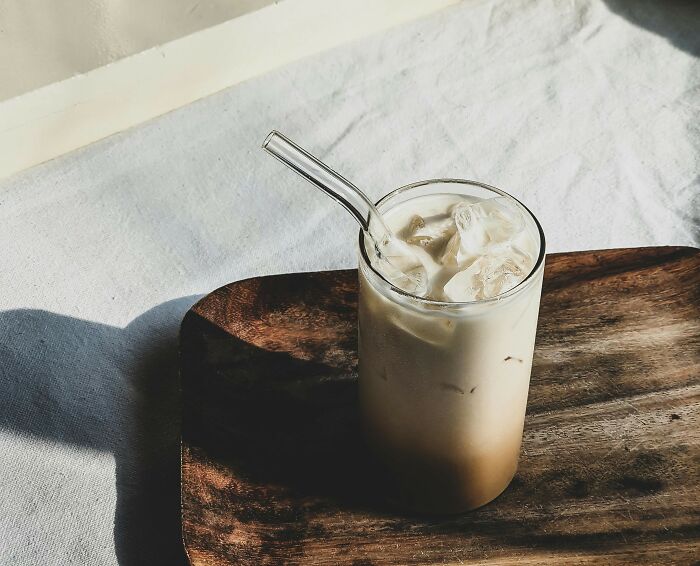 Iced latte on a wooden tray, an affordable treat that feels fancier than it is, with natural light highlighting the drink.