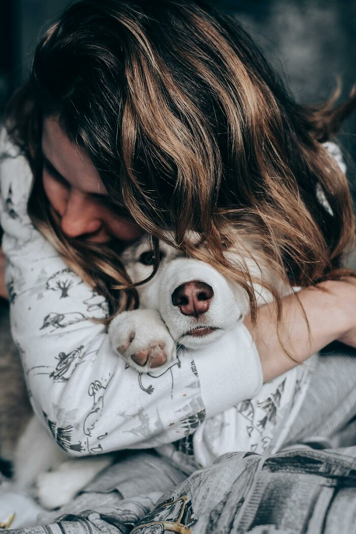 Person hugging a relaxed puppy in pajamas, illustrating an often misunderstood moment of trauma and comfort.