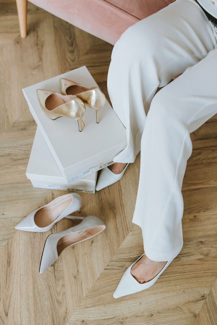 Woman in white pants with high heels and shoe boxes, showcasing fashion choices that confuse men.
