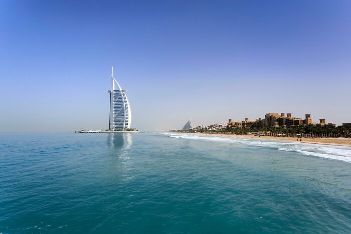 Stunning view of Burj Al Arab by the sea under a clear sky, illustrating a common FOMO-induced tourist experience.
