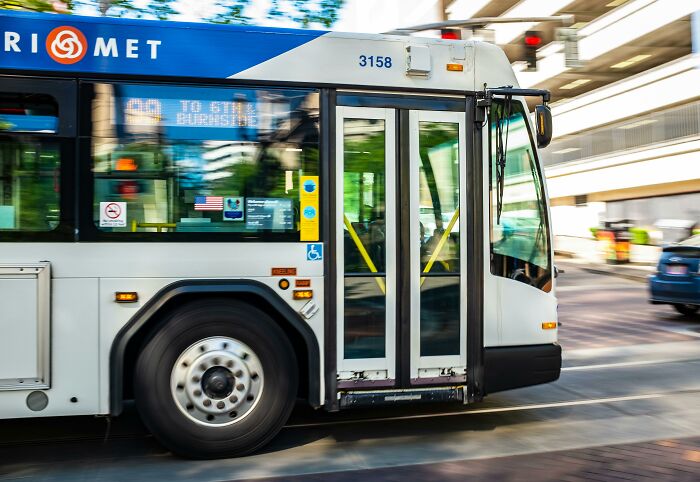 TriMet bus driving on city street, showcasing public transport in an urban setting.