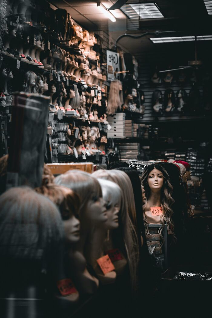 Mannequin heads with wigs on display in a dimly lit store, illustrating unusual and unfortunate lottery stories.