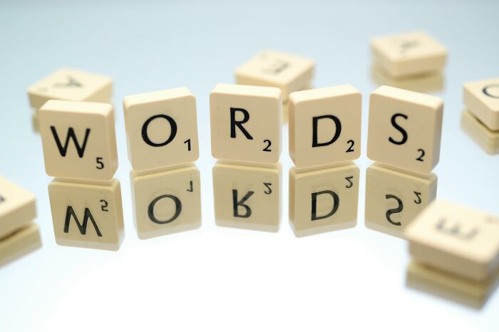 Scrabble letter tiles spelling words reflected on a smooth surface, illustrating tricky anagrams and word challenges.