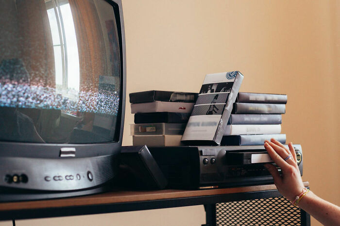 Old TV and VCR with VHS tapes, capturing a weird and nostalgic setup in someone's house.