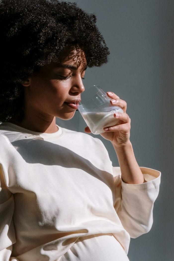 Woman in a light shirt drinking milk, highlighting profession's obvious yet unknown aspects.