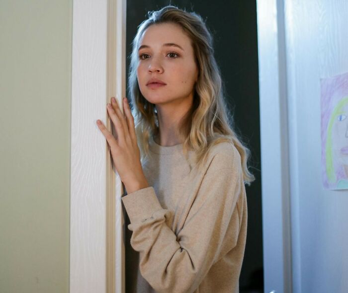 Woman in a doorway, listening to her gut instinct with a thoughtful expression.