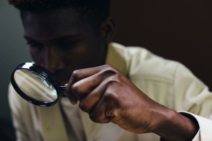 Person closely examining something with a magnifying glass to find differences.