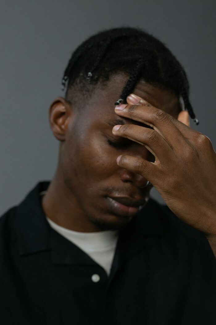 A person looking contemplative with their hand on forehead, reflecting on moving abroad permanently.