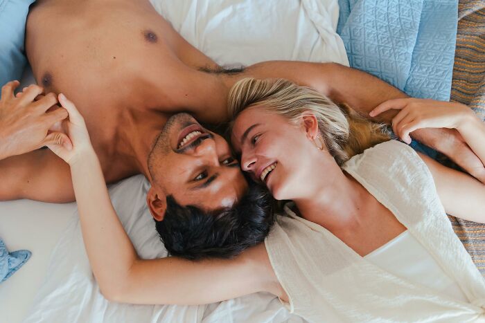 Couple lying on bed smiling and holding hands, conveying things learned in relationships.