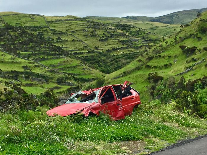 Wrecked red car in a grassy rural area, illustrating a call first responders will remember for the rest of their lives.